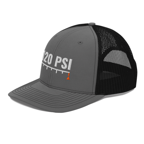 120 PSI Trucker Hat, charcoal and black Richardson 112 mesh-back cap with 120 PSI in white embroidery over a gauge scale with an orange needle, left front angle