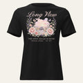 Black Long View Women's Tee, front view with a watercolor floral wreath around a long-nose sleeper truck on a winding road