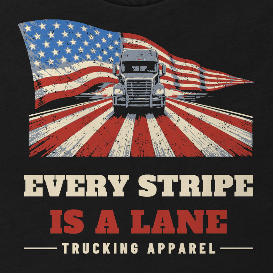 Every Stripe Is a Lane Trucker Flag Tee in black, close-up of the front print: EVERY STRIPE IS A LANE flag print with a semi truck. Design made with AI assistance.