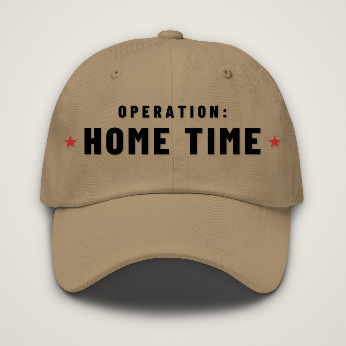 Operation: Home Time Dad Hat, khaki Yupoong 6245CM dad hat with OPERATION: HOME TIME embroidered in black with a red star on each side, front view.