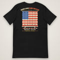 Every Load Flies the Flag Tee in black, back view laid flat showing the EVERY LOAD FLIES THE FLAG back print: an American flag across a trailer's rear swing doors, with DOORS SEALED. FLAG FLYING. and the Trucking Apparel signature.