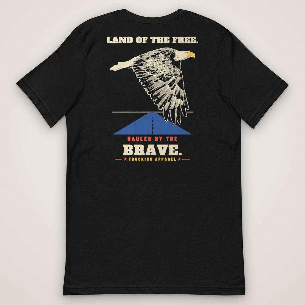 Land of the Free. Hauled by the Brave. Tee in black, back view laid flat showing the LAND OF THE FREE. HAULED BY THE BRAVE. back print: an engraving-style eagle over a highway.