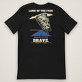 Land of the Free. Hauled by the Brave. Tee in black, back view laid flat showing the LAND OF THE FREE. HAULED BY THE BRAVE. back print: an engraving-style eagle over a highway.