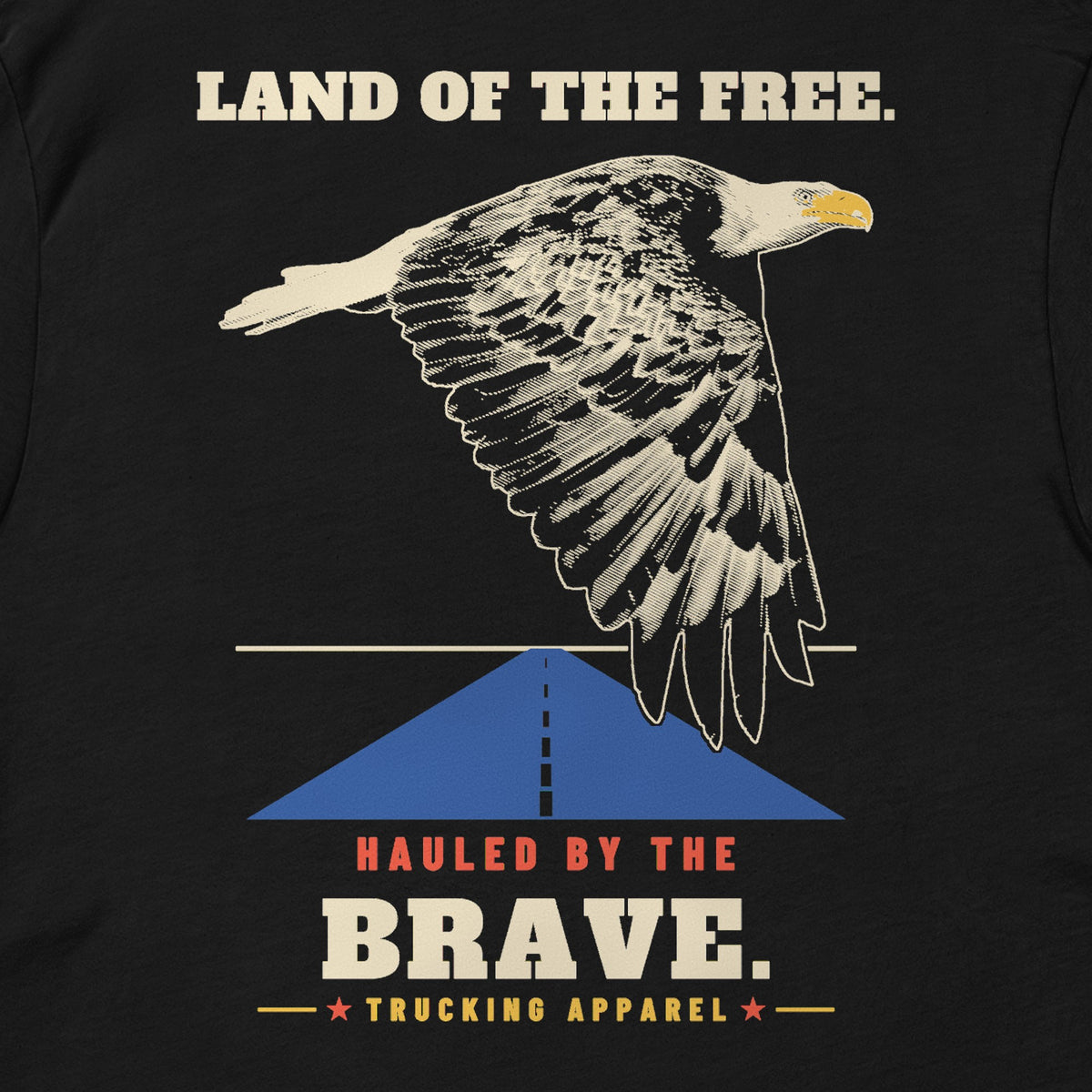 Land of the Free. Hauled by the Brave. Tee in black, close-up of the LAND OF THE FREE. HAULED BY THE BRAVE. back print: an engraving-style eagle over a highway.