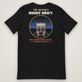 The Nation's Night Shift Tee in black, back view laid flat showing the back print reading THE NATION'S NIGHT SHIFT: a trailer's rear view on a night highway under stars, with WHILE AMERICA SLEEPS, WE ROLL.