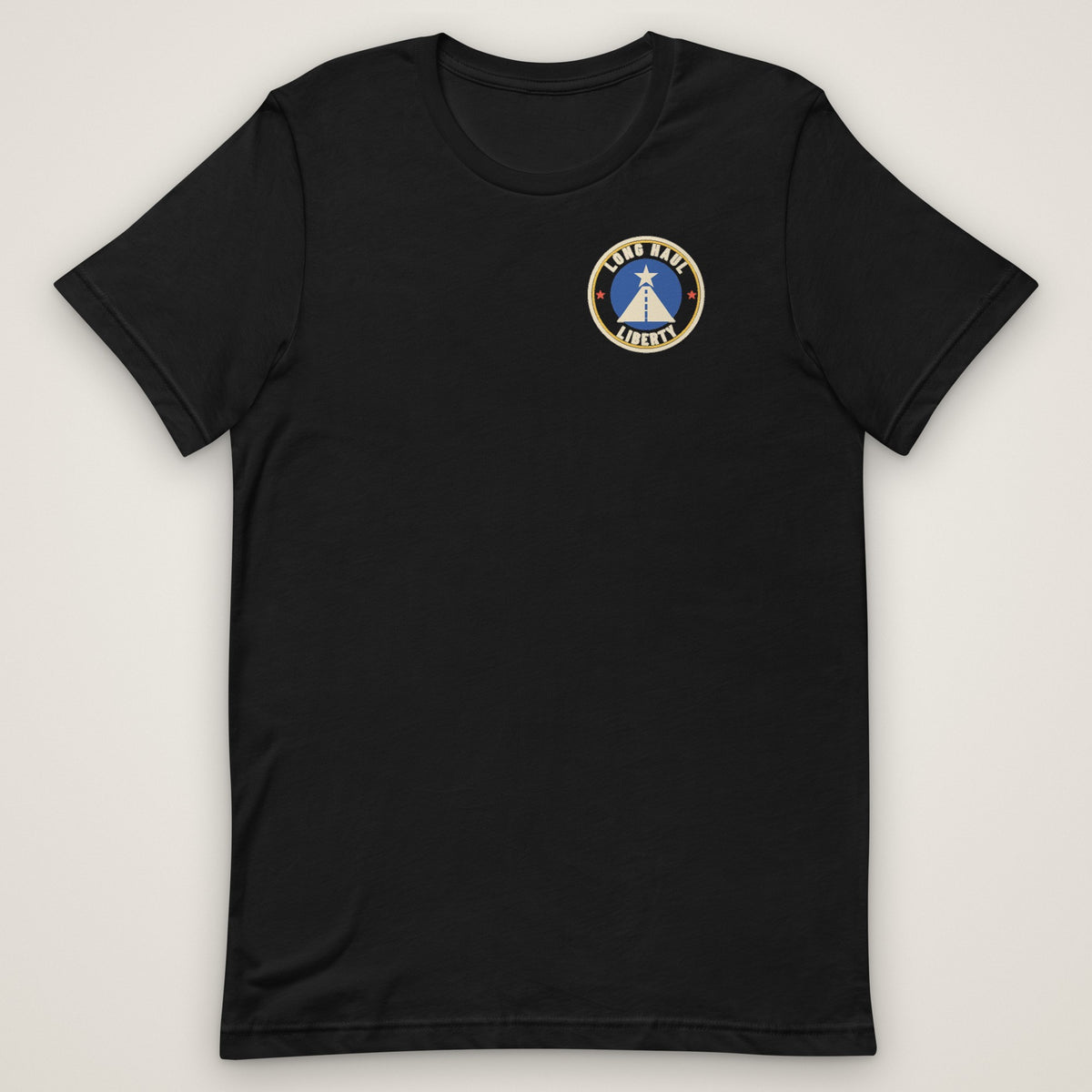 The Nation's Night Shift Tee in black, front view laid flat with the round Long Haul Liberty badge on the left chest.