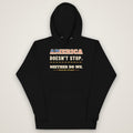 America Doesn't Stop Hoodie in black, front view laid flat showing the AMERICA DOESN'T STOP. NEITHER DO WE. front print with stars-and-stripes lettering.