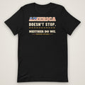 America Doesn't Stop Tee in black, front view laid flat showing the AMERICA DOESN'T STOP. NEITHER DO WE. front print with stars-and-stripes lettering.