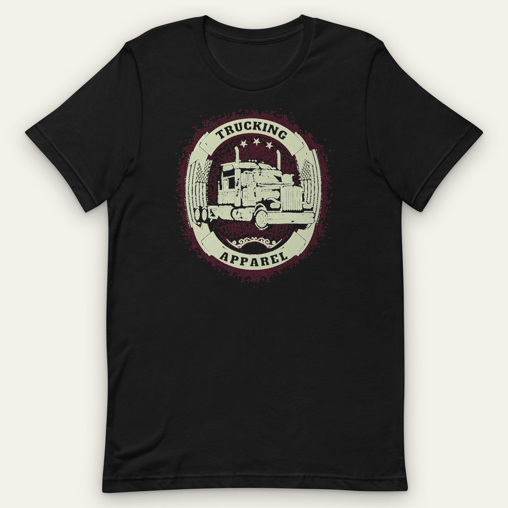 Big Rig Emblem Trucker Tee, front view laid flat showing a cream oval emblem with a big rig, crossed flags and three stars, with TRUCKING and APPAREL on solid bands.