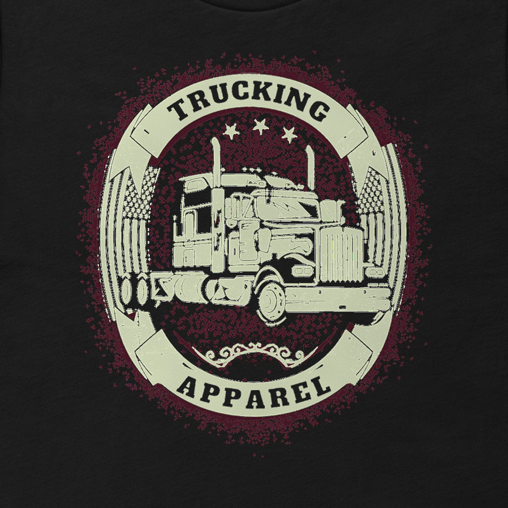 Big Rig Emblem Trucker Tee, close-up of a cream oval emblem with a big rig, crossed flags and three stars, with TRUCKING and APPAREL on solid bands.